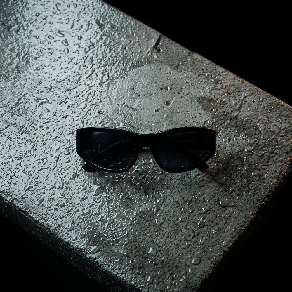 Overhead view of black sunglasses on wet raw concrete